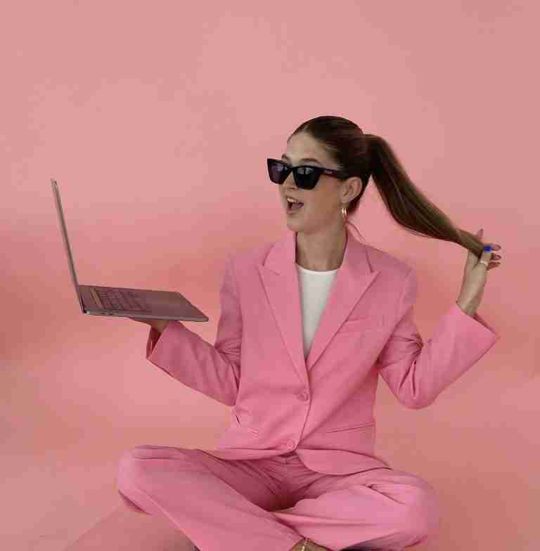 girl holding a laptop and her pony tail looking happy